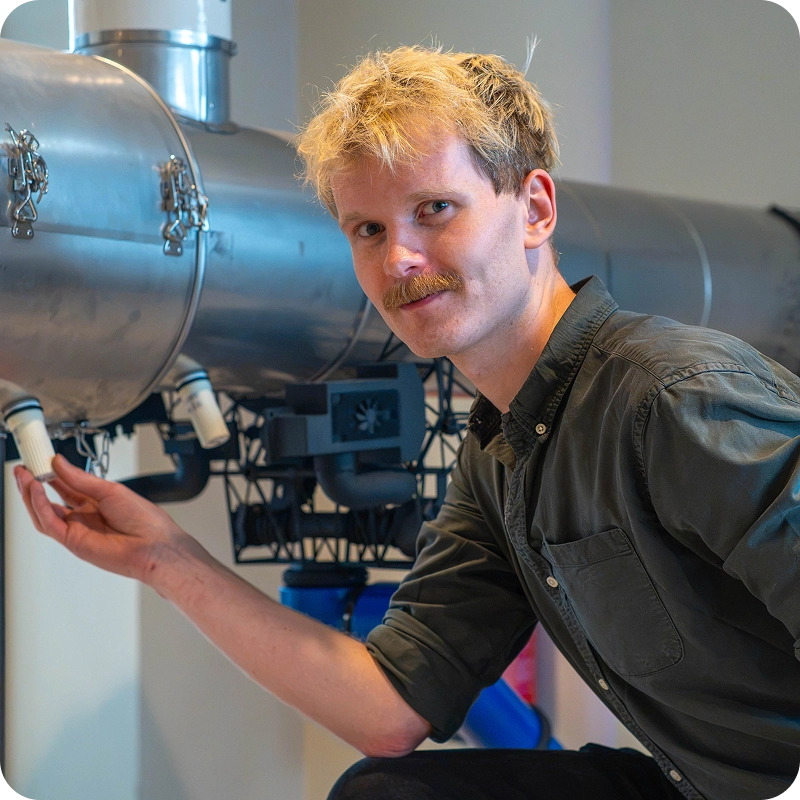 Runar Reve, Project Manager at bluZenit, inspecting a monitoring sensor on industrial pipework