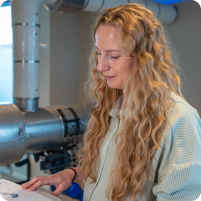 Ruth Silje Serigstad reviewing inspection documentation beside insulated pipework