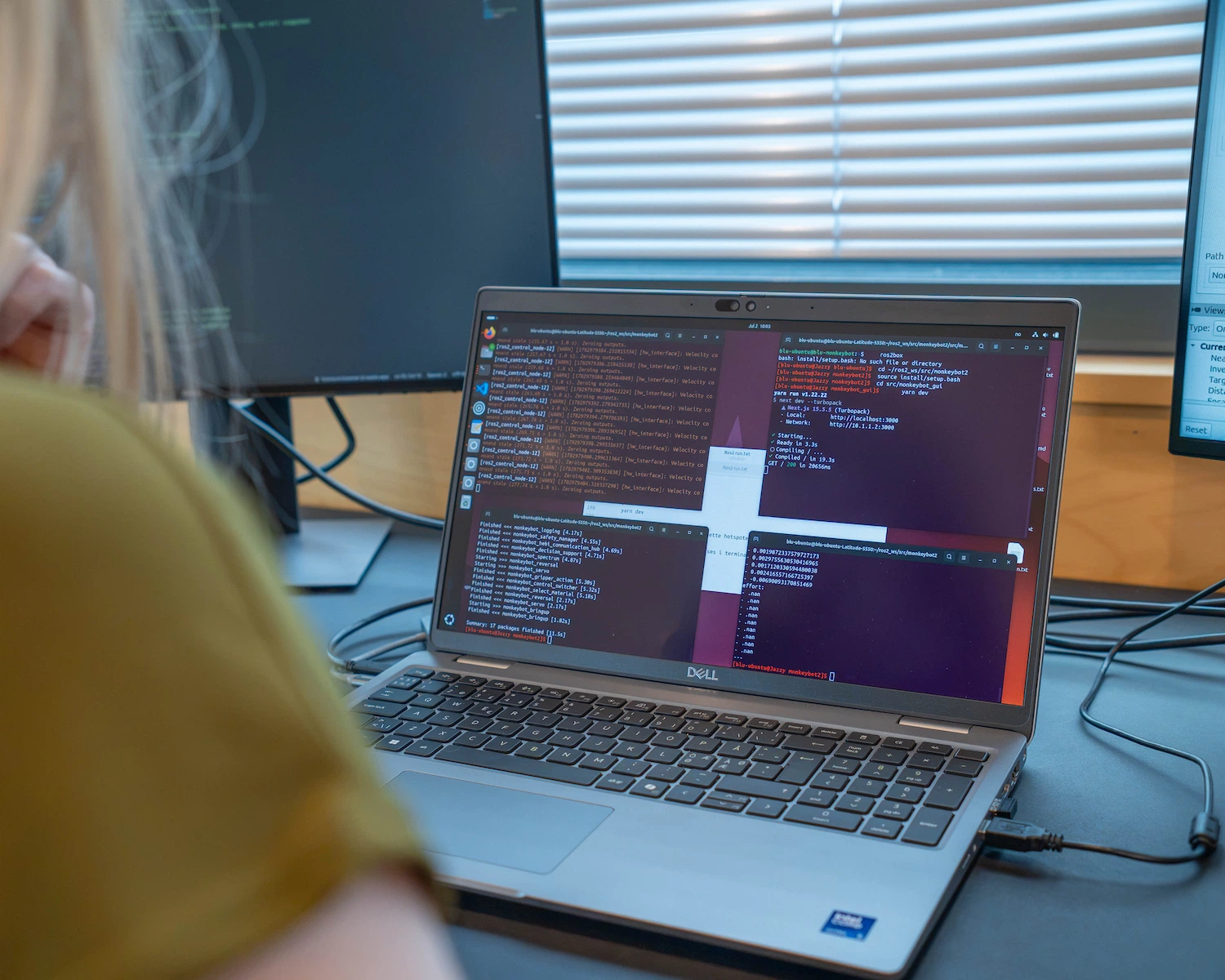 Engineer monitoring ROS2 robotics software and terminal output on a laptop